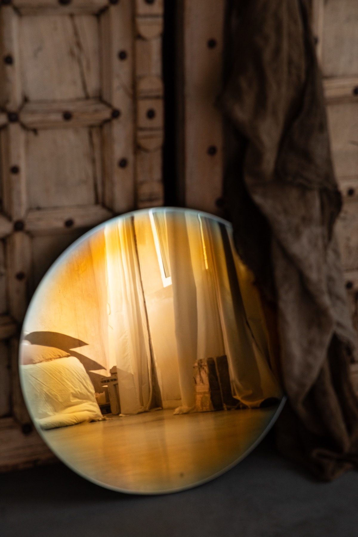 The Saturn mirror leaning against a tribal door, golden and amber reflections