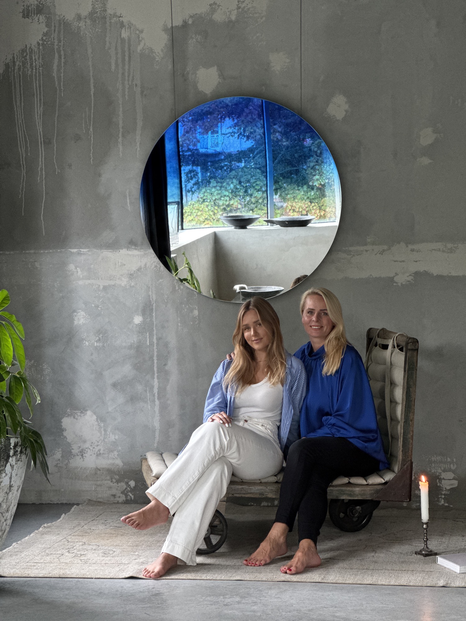 The mother and daughter founders of MORPH seated beneath one of their blue Neptune mirrors